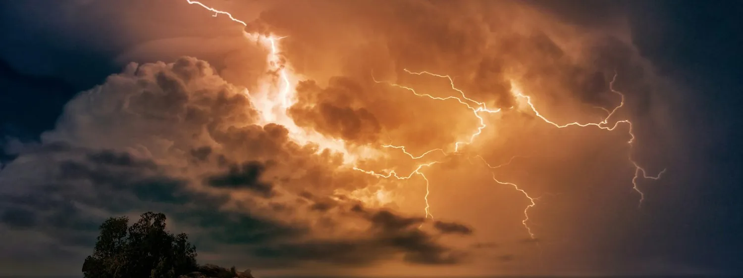 A lightning storm breaking over open water at dusk