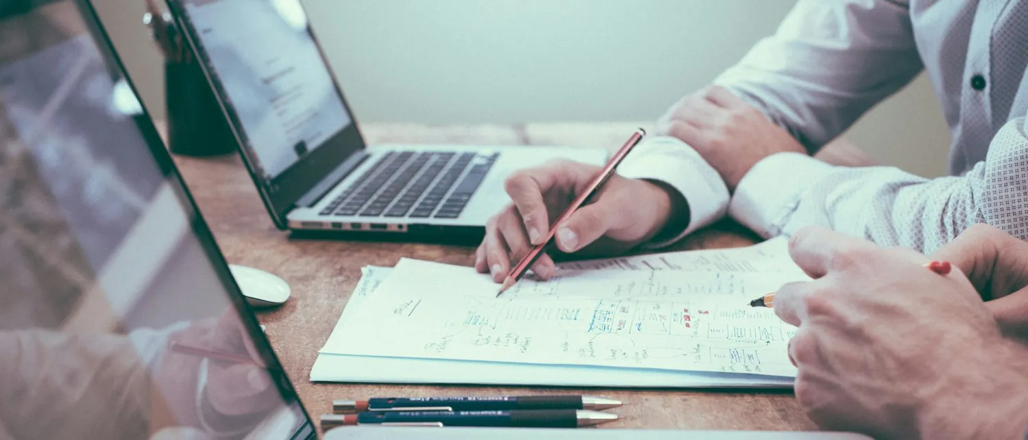 A senior actuary working through a reserving book by hand — pen, worksheet, and laptop